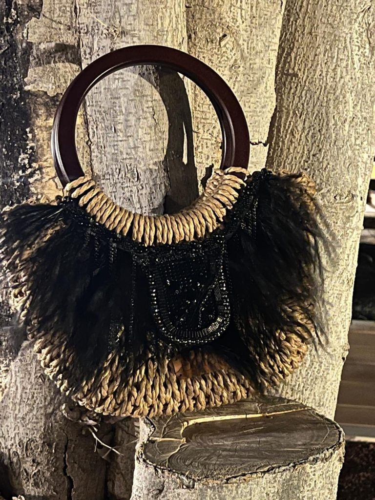 Bolso con asa de madera, adornado con flecos y detalles en brillantes.